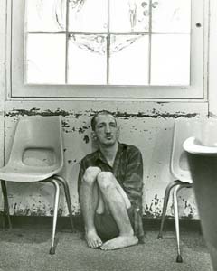 Seated on floor by radiator