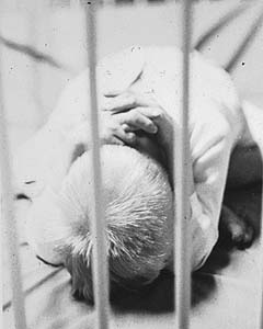 Child curled up behind bars
